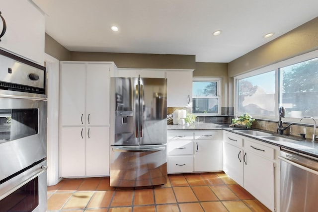 kitchen featuring stainless steel appliances, white cabinetry, sink, and light tile patterned flooring