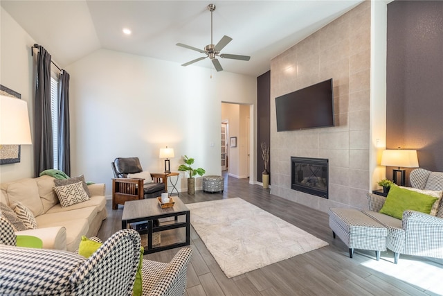 living room with hardwood / wood-style flooring, a tile fireplace, lofted ceiling, and ceiling fan