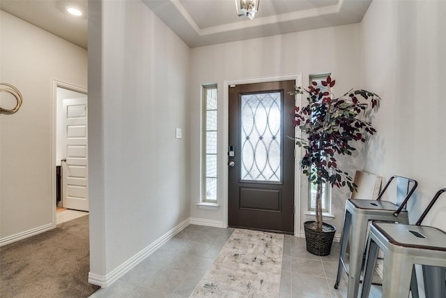 carpeted entrance foyer with a wealth of natural light and a raised ceiling