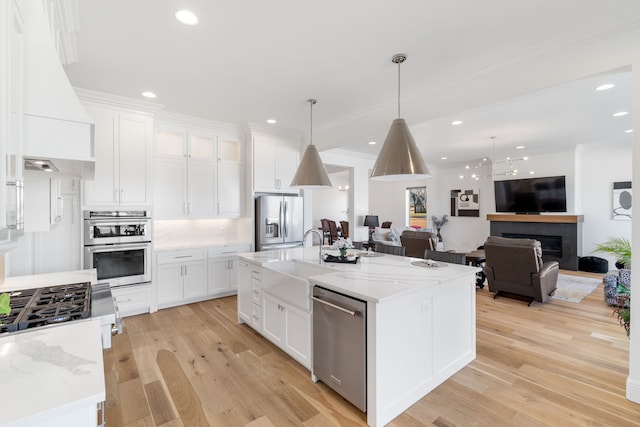 kitchen featuring white cabinetry, stainless steel appliances, custom exhaust hood, and a center island with sink