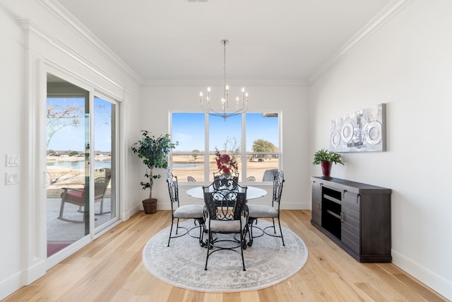 dining space with a water view, plenty of natural light, an inviting chandelier, and light hardwood / wood-style floors