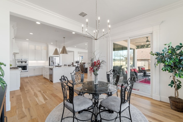 dining area with light wood-style floors, visible vents, crown molding, and a notable chandelier