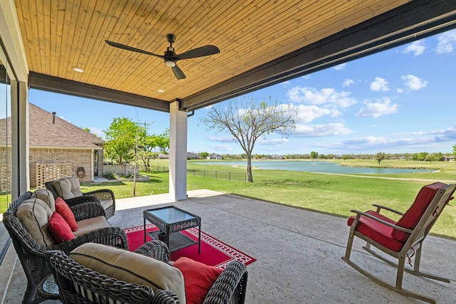 view of patio / terrace featuring a ceiling fan, a water view, and fence