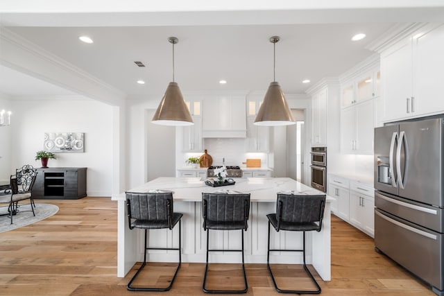 kitchen featuring decorative light fixtures, appliances with stainless steel finishes, a kitchen island, light hardwood / wood-style floors, and white cabinets