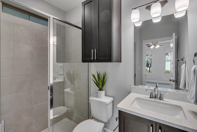 bathroom featuring ceiling fan, vanity, toilet, and a shower with door