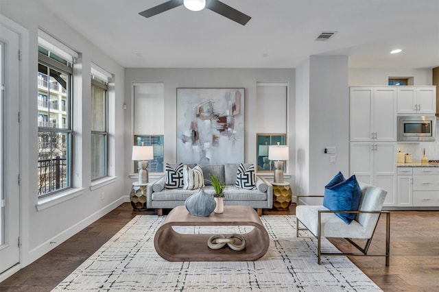 living room with dark hardwood / wood-style flooring and ceiling fan