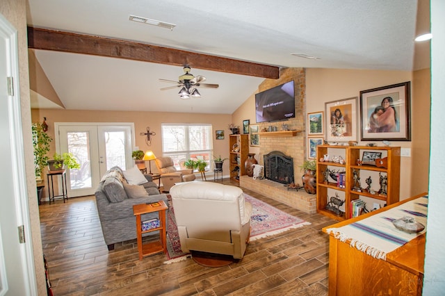 living room featuring ceiling fan, a brick fireplace, and vaulted ceiling with beams