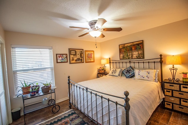 bedroom with ceiling fan, dark hardwood / wood-style flooring, and a textured ceiling