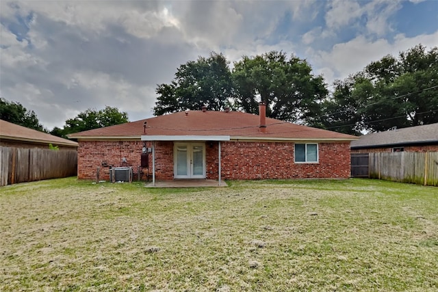 rear view of property with a patio, a lawn, and central air condition unit