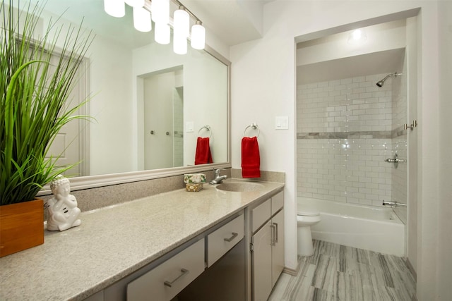 full bathroom with tiled shower / bath, vanity, and toilet