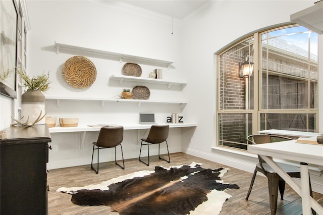 interior space with ornamental molding, built in desk, and light wood-type flooring