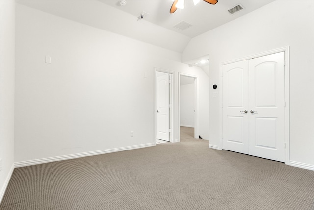 unfurnished bedroom with light colored carpet, ceiling fan, vaulted ceiling, and a closet