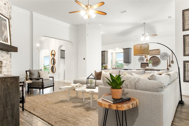 living room featuring crown molding, ceiling fan, a fireplace, and hardwood / wood-style floors