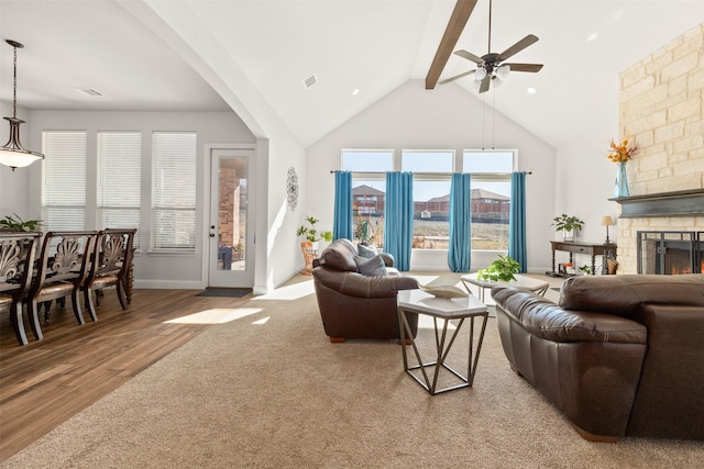 living room with hardwood / wood-style floors, a stone fireplace, lofted ceiling with beams, and ceiling fan