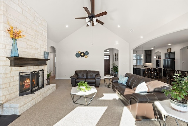 carpeted living room with ceiling fan, a fireplace, and vaulted ceiling