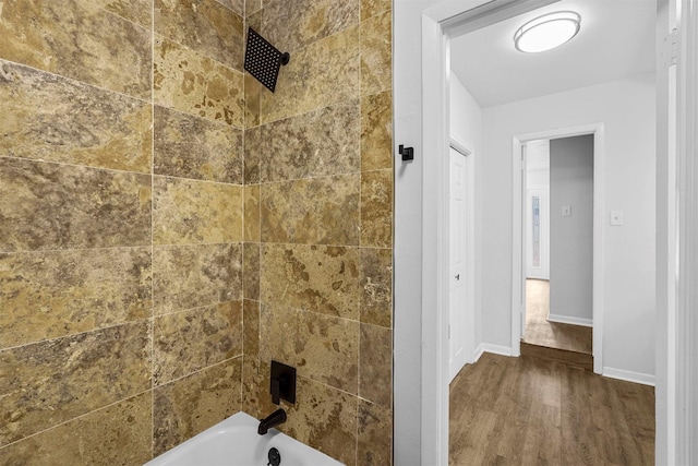 bathroom with hardwood / wood-style floors and tiled shower / bath