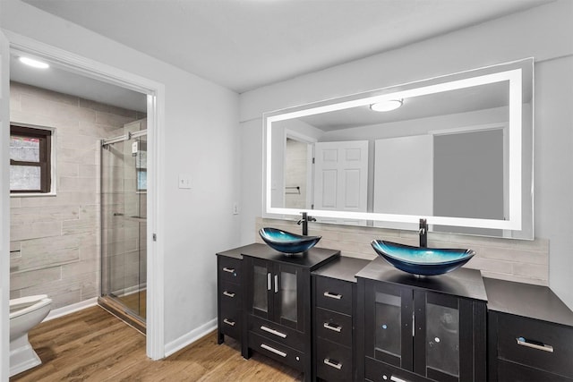 bathroom with hardwood / wood-style flooring, vanity, backsplash, and walk in shower