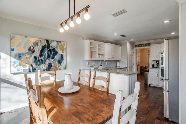 dining space with crown molding, sink, and dark wood-type flooring