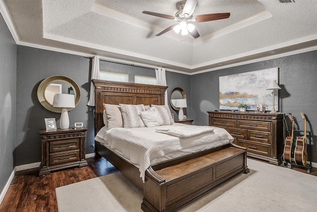 bedroom with dark hardwood / wood-style floors, ornamental molding, ceiling fan, a raised ceiling, and a textured ceiling