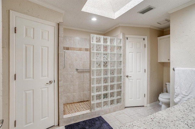 bathroom with crown molding, tile patterned flooring, tiled shower, a textured ceiling, and toilet