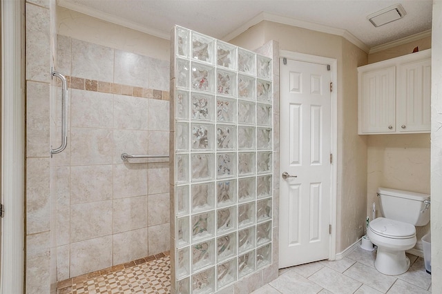 bathroom with tile patterned flooring, ornamental molding, a tile shower, and toilet