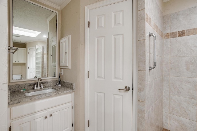 bathroom with tiled shower, crown molding, a skylight, a textured ceiling, and vanity