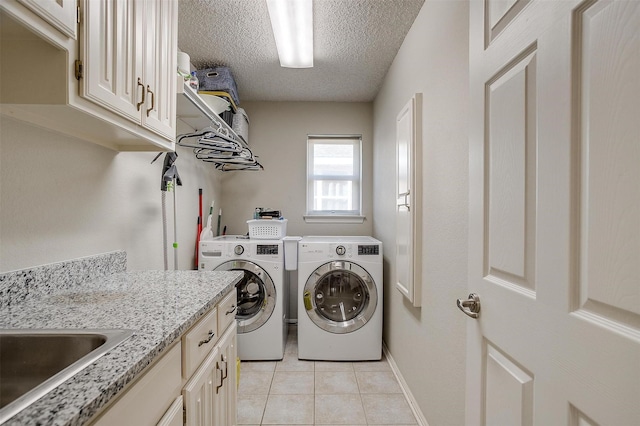 clothes washing area with cabinets, separate washer and dryer, a textured ceiling, and light tile patterned floors