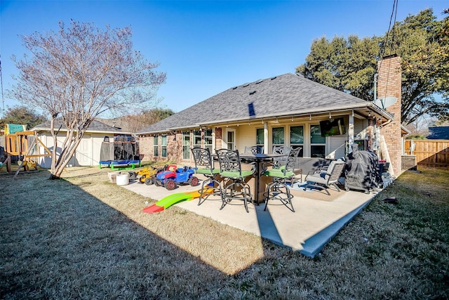 rear view of property with a playground, a patio, a yard, and a trampoline