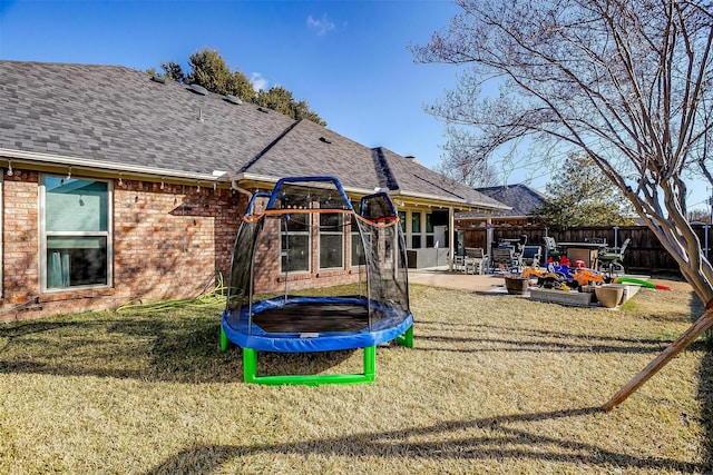 rear view of house with a yard, a patio area, and a trampoline