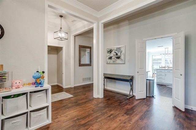 entrance foyer with dark hardwood / wood-style flooring, crown molding, and an inviting chandelier