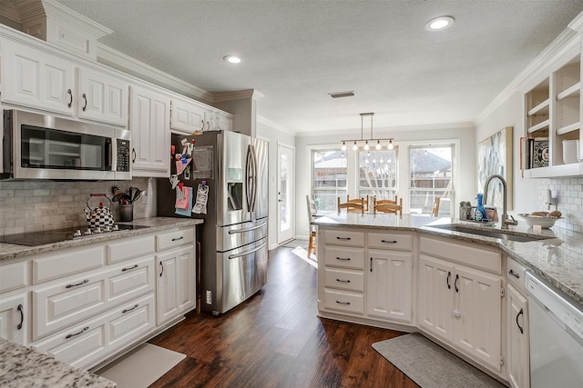 kitchen featuring stainless steel appliances, sink, white cabinets, and decorative light fixtures