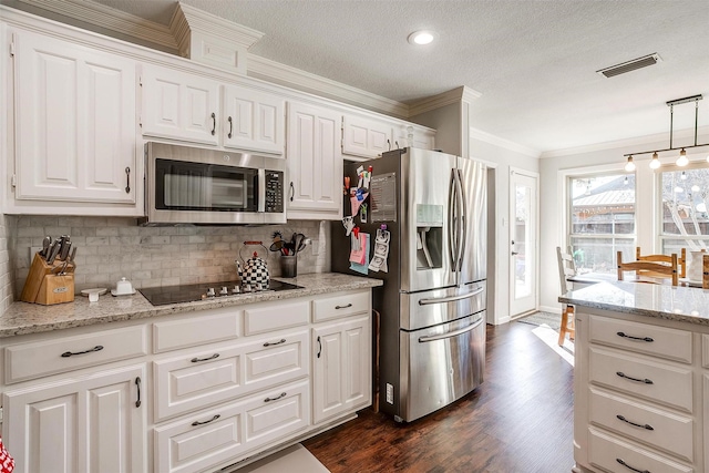 kitchen with hanging light fixtures, appliances with stainless steel finishes, white cabinets, and backsplash