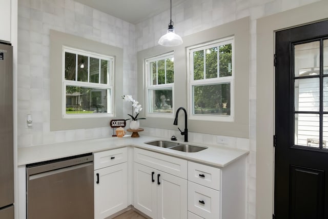 kitchen featuring white cabinetry, dishwasher, sink, and decorative light fixtures