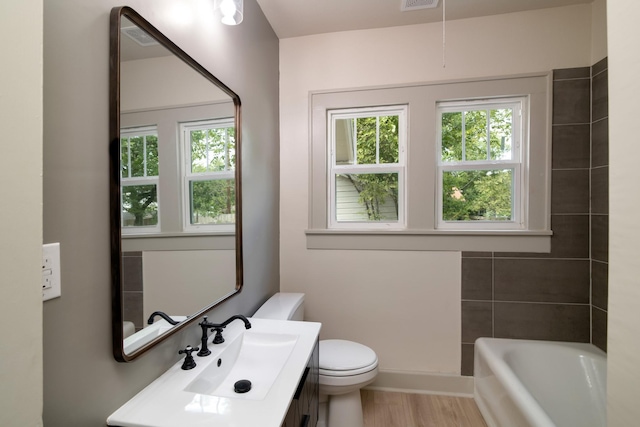 bathroom featuring hardwood / wood-style flooring, vanity, toilet, and a tub