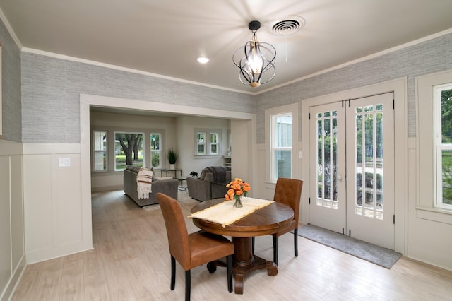 dining area with ornamental molding, a chandelier, light wood-type flooring, and a wealth of natural light