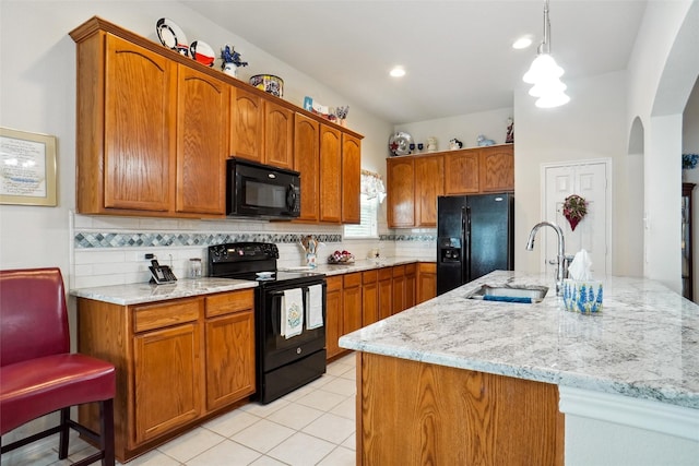 kitchen featuring pendant lighting, sink, decorative backsplash, light stone counters, and black appliances