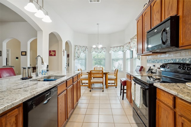 kitchen with sink, light tile patterned floors, pendant lighting, light stone countertops, and black appliances