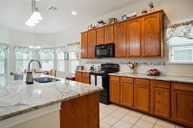 kitchen with sink, tasteful backsplash, decorative light fixtures, light stone countertops, and black appliances