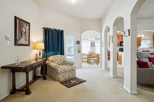 living area featuring a notable chandelier, a towering ceiling, a wealth of natural light, and light colored carpet