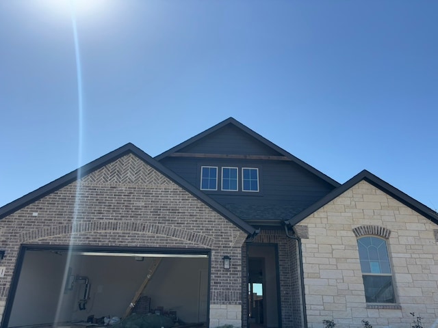 view of front of house with an attached garage, brick siding, and a shingled roof