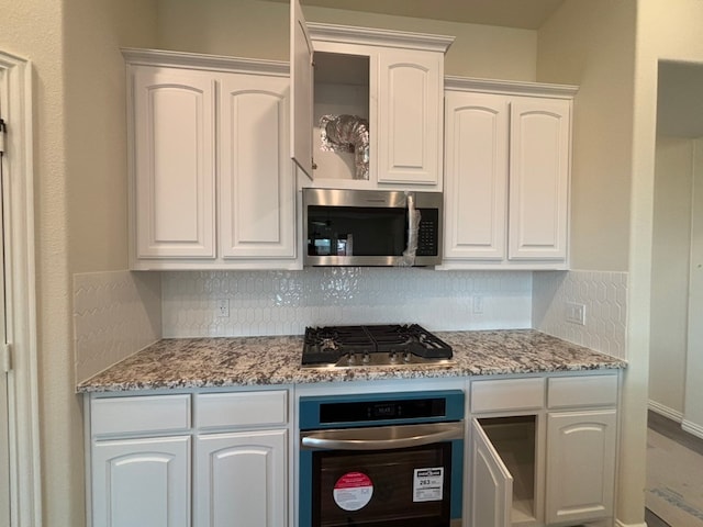 kitchen featuring stainless steel appliances, backsplash, and white cabinets