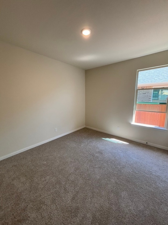 carpeted spare room with baseboards