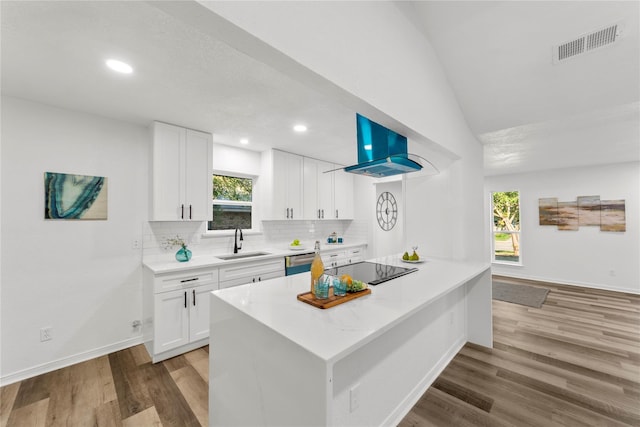 kitchen featuring sink, white cabinetry, vaulted ceiling, kitchen peninsula, and island exhaust hood