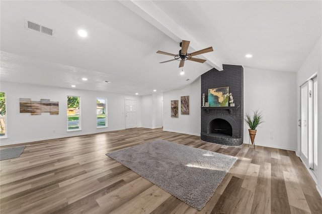 living room with ceiling fan, a fireplace, lofted ceiling with beams, and light hardwood / wood-style flooring