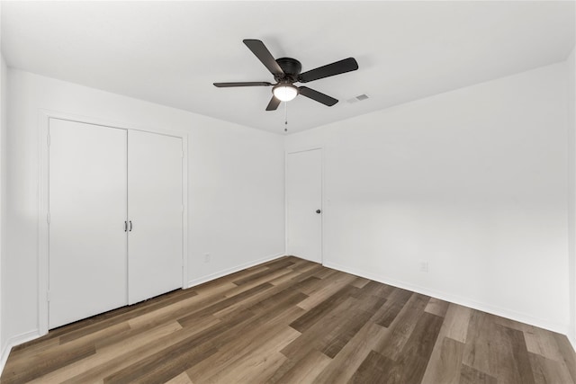 unfurnished bedroom featuring dark wood-type flooring, a closet, and ceiling fan