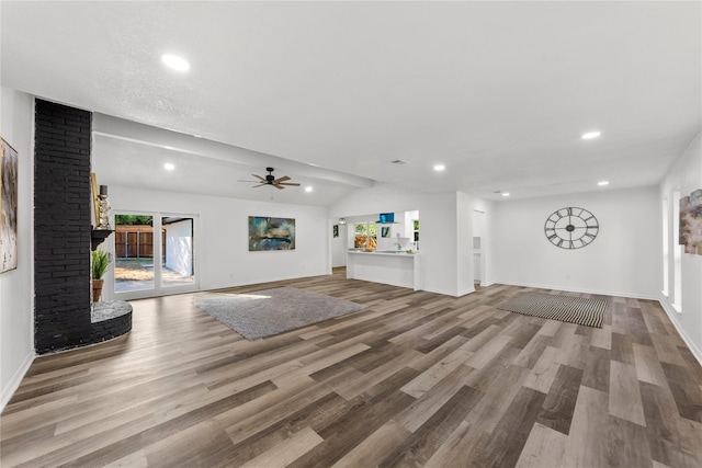 unfurnished living room with vaulted ceiling, ceiling fan, hardwood / wood-style floors, and a brick fireplace