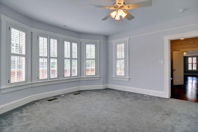 spare room featuring ceiling fan and dark colored carpet