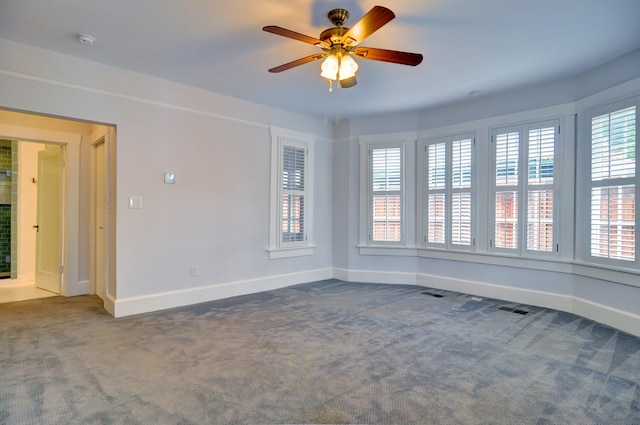 carpeted empty room with a wealth of natural light and ceiling fan