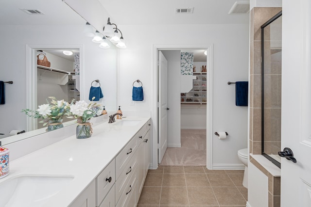 bathroom with toilet, visible vents, a walk in closet, and a sink