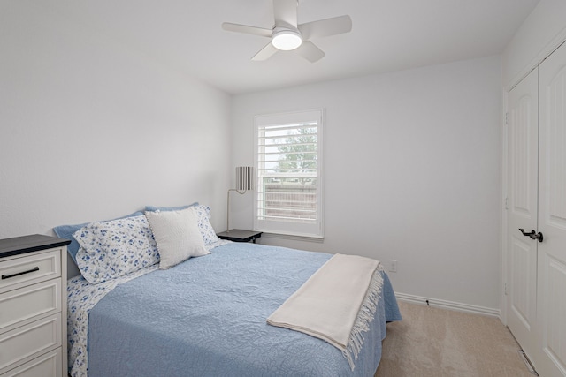 bedroom featuring a ceiling fan, baseboards, a closet, and light colored carpet